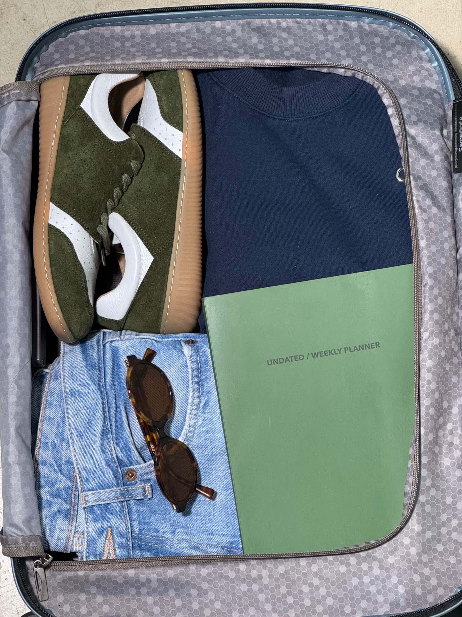Open travel suitcase neatly packed with green-white GOSH barefoot