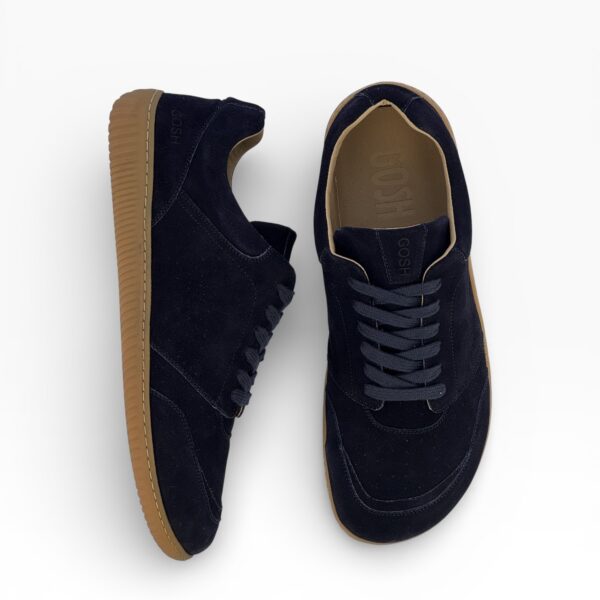 Side-top view of a barefoot blue suede shoe