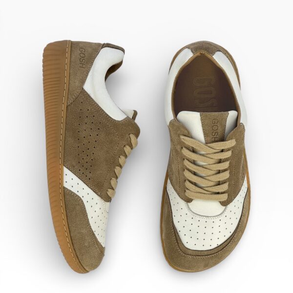 Side-top view of a barefoot beige-white suede shoe