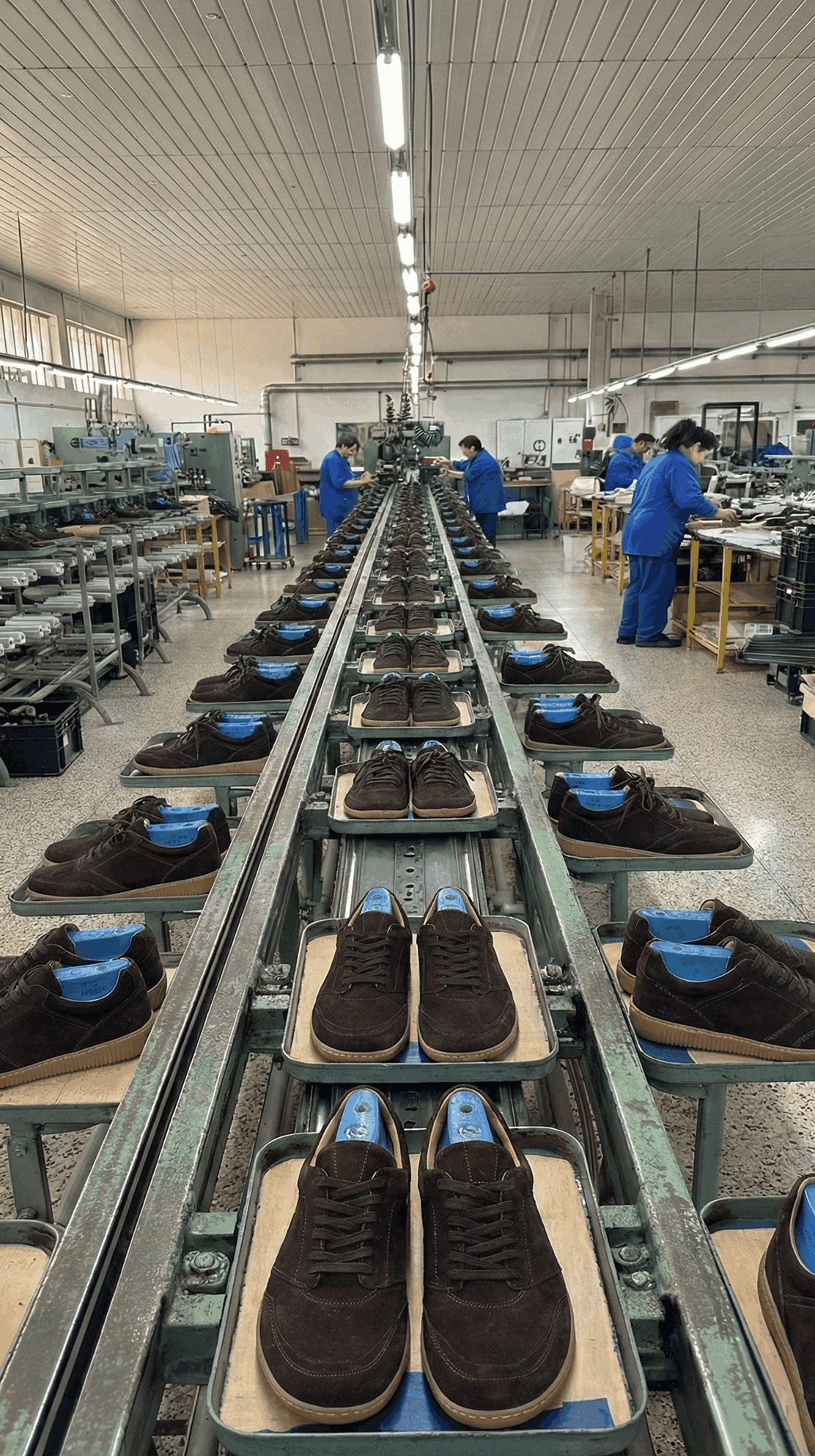 A shoe production line where finished shoes move along a conveyor as workers handle and check them